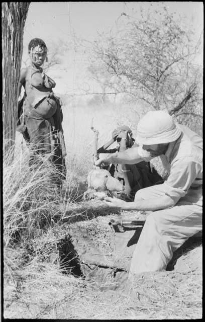 //Kushay standing next to Robert Story sitting pulling out a root