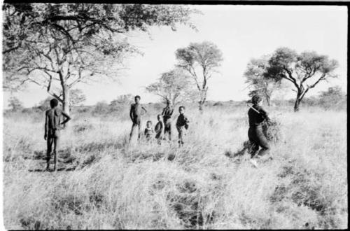 Group of people standing in the grass, and Elizabeth Marshall Thomas carrying brush