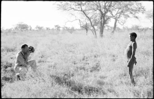 Gao, father of N!aba, standing and posing, and William Donellan photographing him