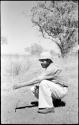 Robert Story crouching and holding a plant specimen, a tall stem of a plant