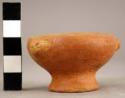 Miniature ring base red vessel with applique stylized heads 4 cm diam.