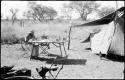 Robert Story sitting at a table in the expedition camp at tea-time