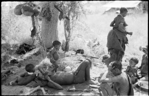 Di!ai walking, seen from the back, her two sons talking to "Lame≠Gao" who is lying beside them, and Norna to the right