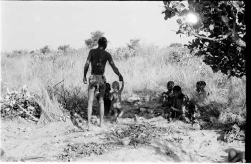 !Gai holding N!whakwe's hand, four people sitting