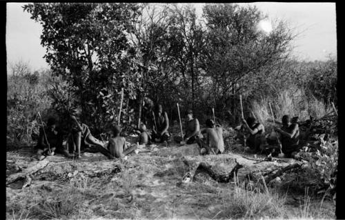 Group of people sitting in a circle, all chopping tsama melons with their digging sticks