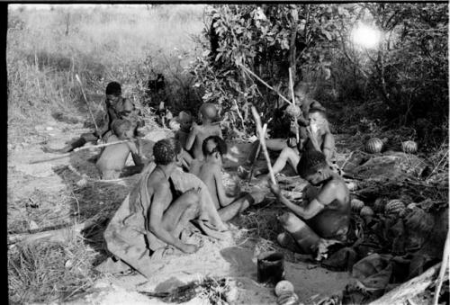 Group of people sitting, eating tsama melons