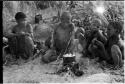 DaSi!Na and /Twikwe cooking something in a pot, two boys sitting