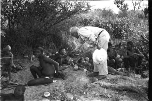 Laurence Marshall shaking hands with Tsekue, !Gai sitting beside Tsekue