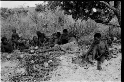 Oukwane holding cord with his toes, group sitting beside him