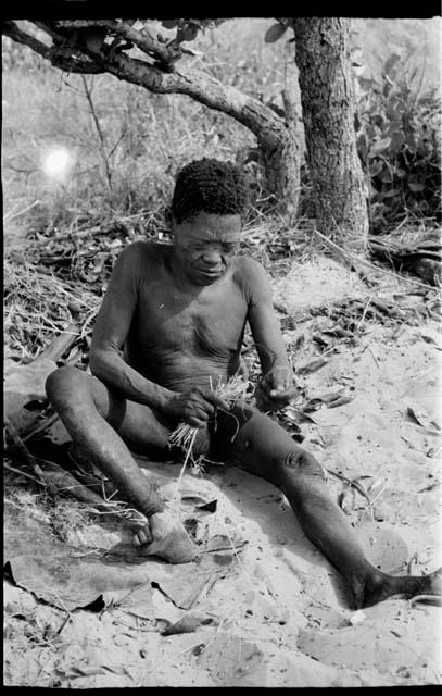 Oukwane holding cord in his toes, smoothing cord with grass