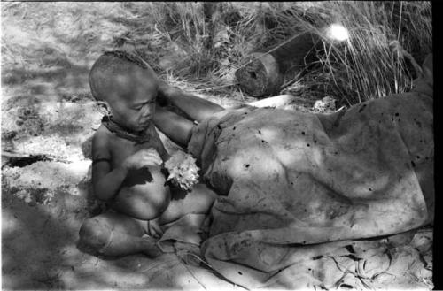 N!whakwe sitting with a cucumber