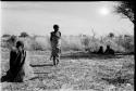 /Twikwe clearing ground with digging stick, someone standing nearby; two children lying in the shade