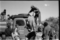 Oukwane on expedition truck, Kernel Ledimo helping someone up; Elizabeth Marshall Thomas and other people in front of expedition truck