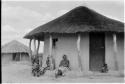 Three women and a child sitting against the outside of a house