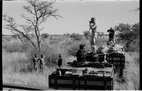 Wilhelm Camm talking to two men; Daniel Blitz photographing from top of the truck with Laurence Marshall and two expedition members