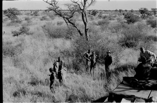 Man being led by a man with a stick, Wilhelm Camm standing with two other men