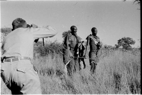 Blind man being led by another man, Daniel Blitz photographing