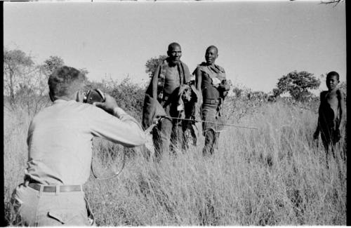 Blind man being led by another man and a boy standing to the side, Daniel Blitz photographing