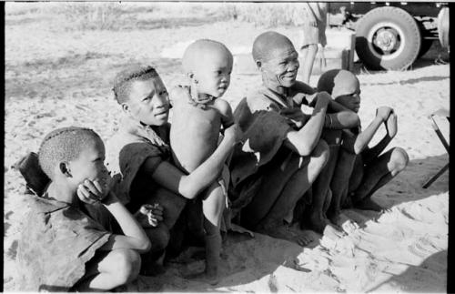 /Gaiamakwe, N!whakwe in front of Tsekue, /Twikwe, and !Oukabe, expedition truck in background
