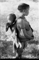 Tsekue carrying N!whakwe on her back