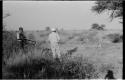 Laurence Marshall and John Marshall, with a gun, standing in a field with a mamba hole