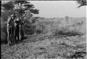 Casper Kruger standing with a stick, John Marshall aiming a shot gun, and Laurence Marshall taking a photograph