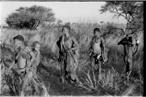 Tsekue carrying N!whakwe, two other women, and a boy dancing