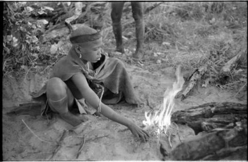 Young woman sitting by a fire