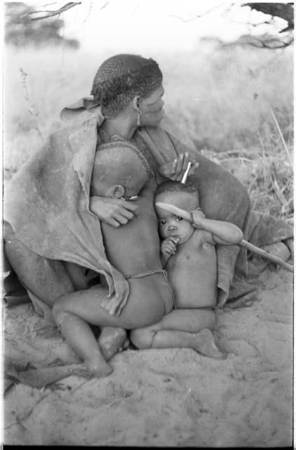 Woman from "visiting group" sitting with two children leaning against her