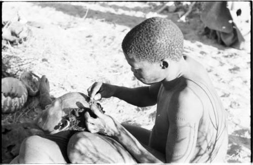 !Gai seated, cutting another man's hair, close-up