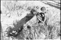 !Gai seated, cutting another man's hair, seen from behind