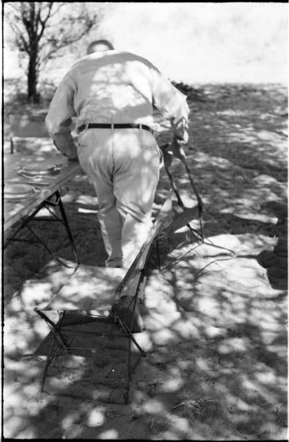 Laurence Marshall picking up a chair, seen from behind