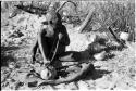 Oukwane playing a musical bow, seated