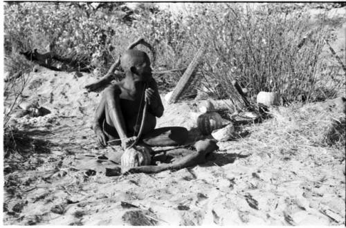 Oukwane playing a musical bow, seated