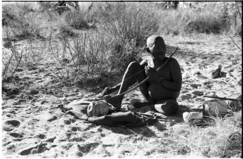 Oukwane playing a musical bow, seated