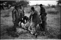 Men skinning a gemsbok, surrounded by a group of people watching