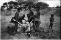 Men skinning a gemsbok, with a group of people watching