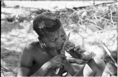 Tsekue eating meat, cutting a bite off at her lips with a knife