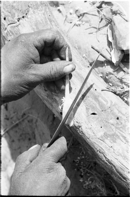 Close-up of a person's hands sharpening an arrow