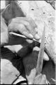 Close-up of a person's hands sharpening an arrow