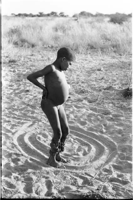 Boy with dance rattles tied to his ankles, dancing in a circle