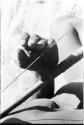 Close-up of Oukwane's hand demonstrating how to play a musical bow