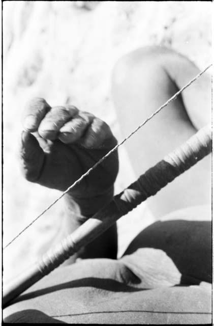 Close-up of Oukwane's hand demonstrating how to play a musical bow