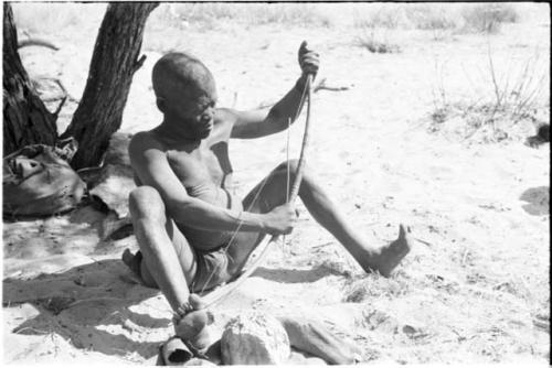 Oukwane seated, playing a bow