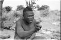 Visiting man demonstrating hunting hand signals, half figure seated