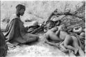 Visiting woman lying in her place in her werft with her child lying on her asleep, with a girl sitting by them