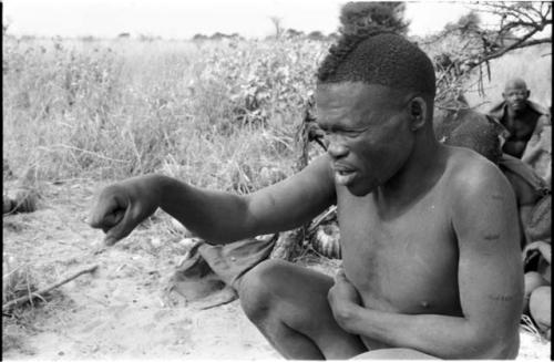 Visiting man demonstrating huntinghand signals, half figure seated