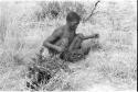 !Gai squatting in the grass holding a carrying net