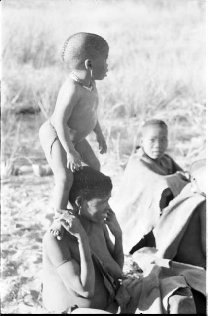 N!whakwe standing on his mother Tsekue's shoulders