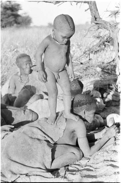 N!whakwe standing on his mother Tsekue's back